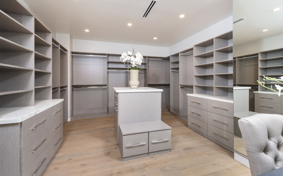 This is an example of an expansive modern gender neutral walk-in wardrobe in Los Angeles with light hardwood flooring.