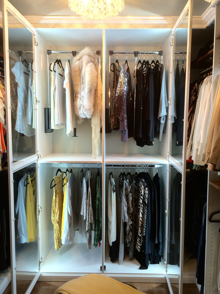 Diseño de armario vestidor unisex retro de tamaño medio con armarios con paneles con relieve, puertas de armario blancas y suelo de madera en tonos medios