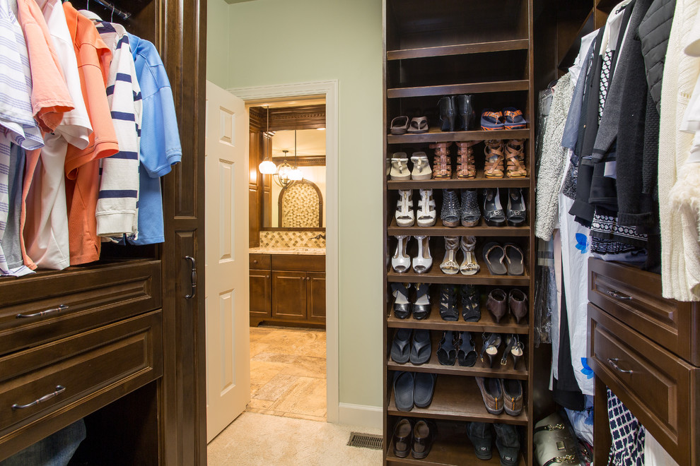 Ejemplo de armario y vestidor tradicional extra grande con armarios con paneles con relieve, puertas de armario de madera en tonos medios y suelo de travertino
