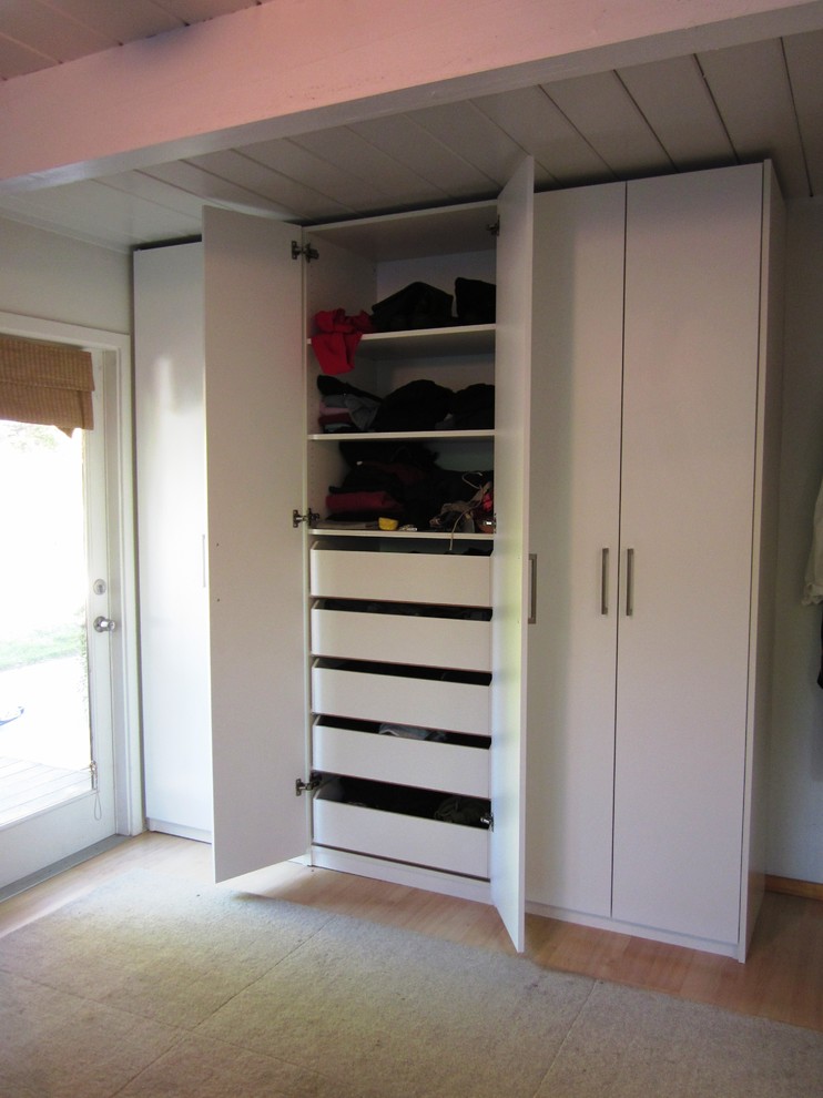 Exemple d'un dressing room tendance de taille moyenne et neutre avec un placard à porte plane, des portes de placard blanches et parquet clair.