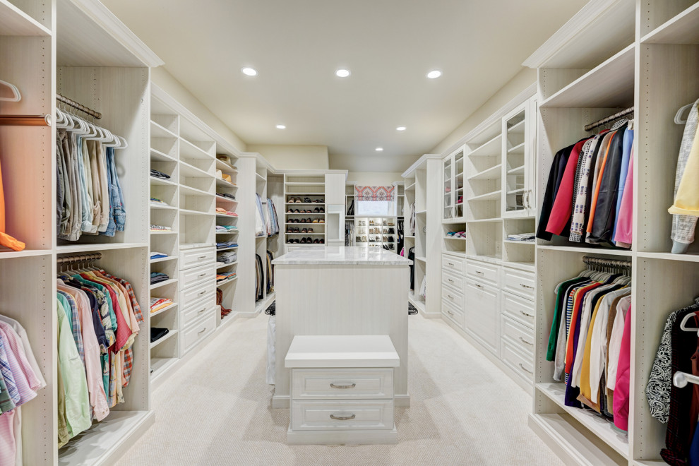Inspiration for a large traditional gender neutral dressing room in Oklahoma City with raised-panel cabinets, light wood cabinets, carpet and beige floors.