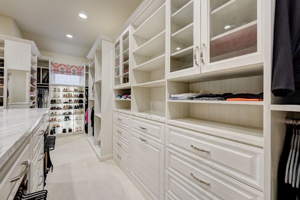 Ejemplo de vestidor unisex clásico renovado grande con armarios con paneles con relieve, puertas de armario de madera clara, moqueta y suelo beige