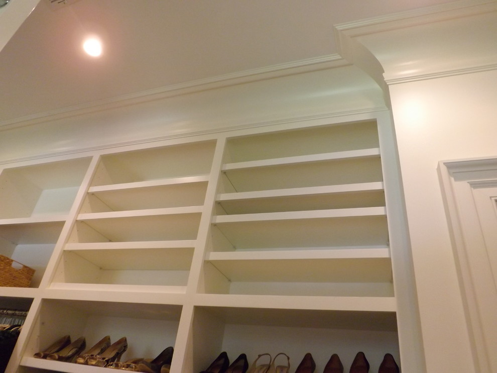 Imagen de armario vestidor unisex clásico grande con puertas de armario blancas, armarios con paneles empotrados y suelo de madera en tonos medios