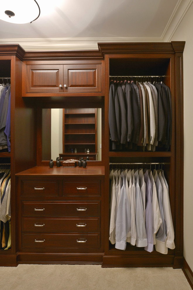 Medium sized classic walk-in wardrobe for men in New York with raised-panel cabinets, dark wood cabinets, carpet and beige floors.
