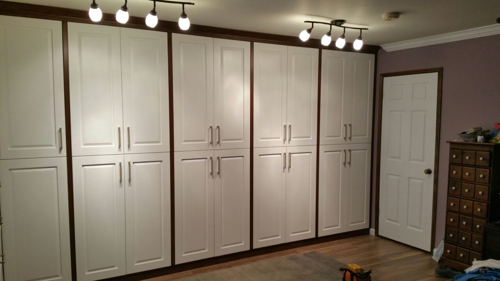 Inspiration for a mid-sized contemporary gender-neutral light wood floor walk-in closet remodel in San Diego with raised-panel cabinets and white cabinets