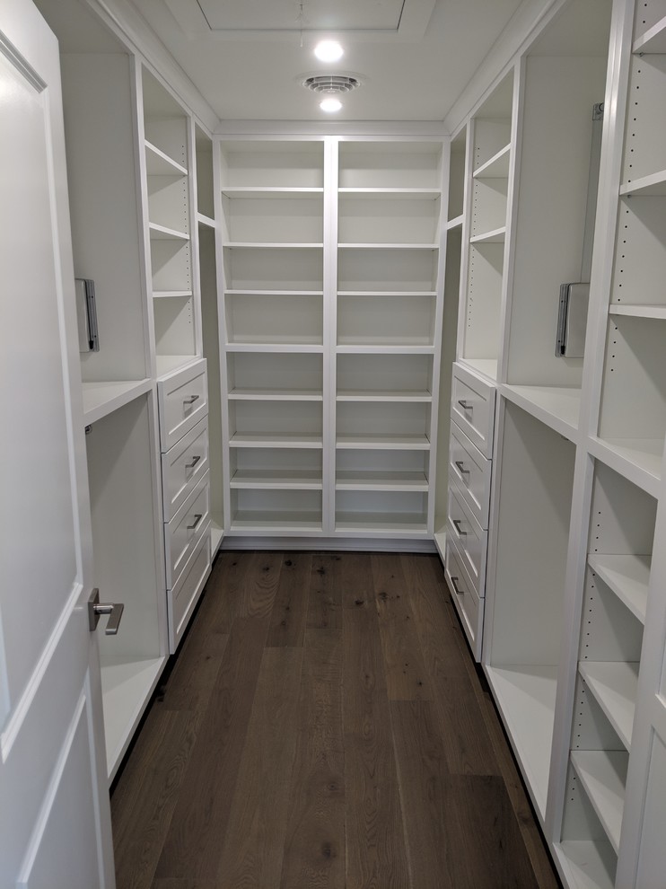 Foto di una cabina armadio unisex chic con ante in stile shaker, ante bianche, pavimento in legno massello medio e pavimento marrone