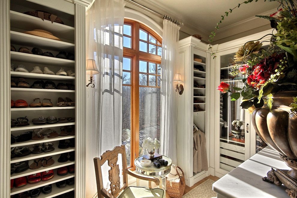 Imagen de vestidor clásico con puertas de armario blancas y suelo de madera clara
