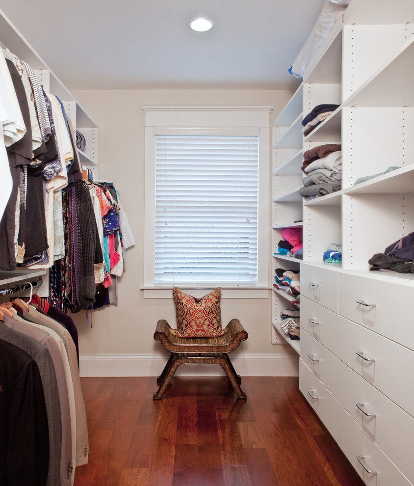 Modelo de armario vestidor unisex tradicional de tamaño medio con armarios con paneles lisos, puertas de armario blancas, suelo de madera en tonos medios y suelo marrón
