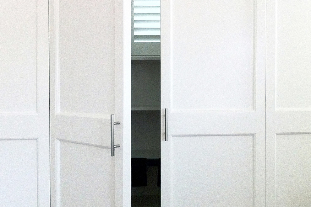 Cette image montre un placard dressing craftsman de taille moyenne et neutre avec un placard à porte shaker et des portes de placard blanches.