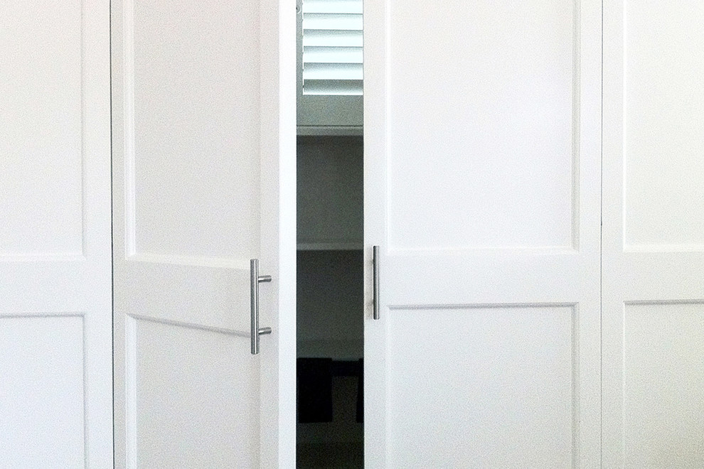 Example of a mid-sized arts and crafts gender-neutral reach-in closet design in Orange County with shaker cabinets and white cabinets