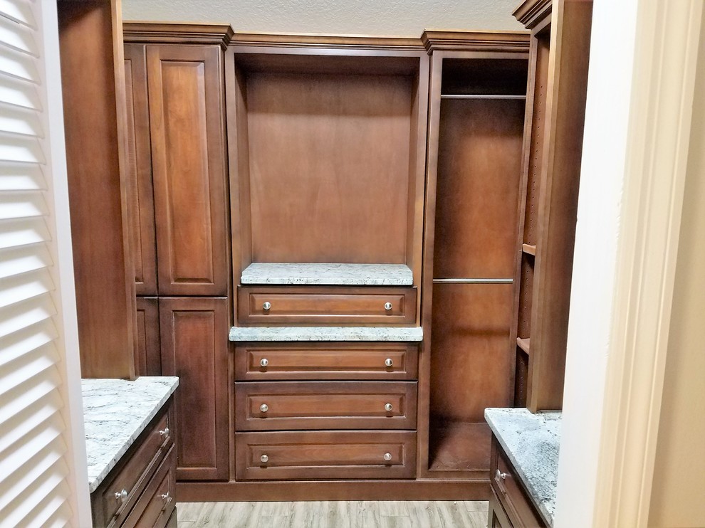 This is an example of a medium sized classic gender neutral walk-in wardrobe in Orlando with raised-panel cabinets, medium wood cabinets and porcelain flooring.