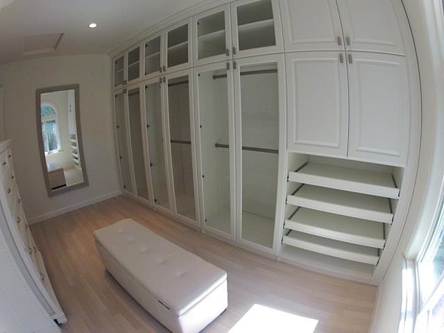 Cette image montre un dressing room craftsman de taille moyenne pour un homme avec un placard avec porte à panneau encastré, des portes de placard blanches, parquet clair et un sol beige.