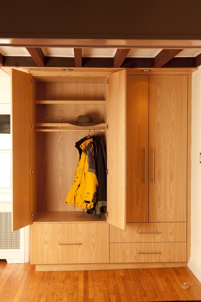На фото: шкаф в нише среднего размера, унисекс в стиле модернизм с плоскими фасадами, светлыми деревянными фасадами, паркетным полом среднего тона и коричневым полом с