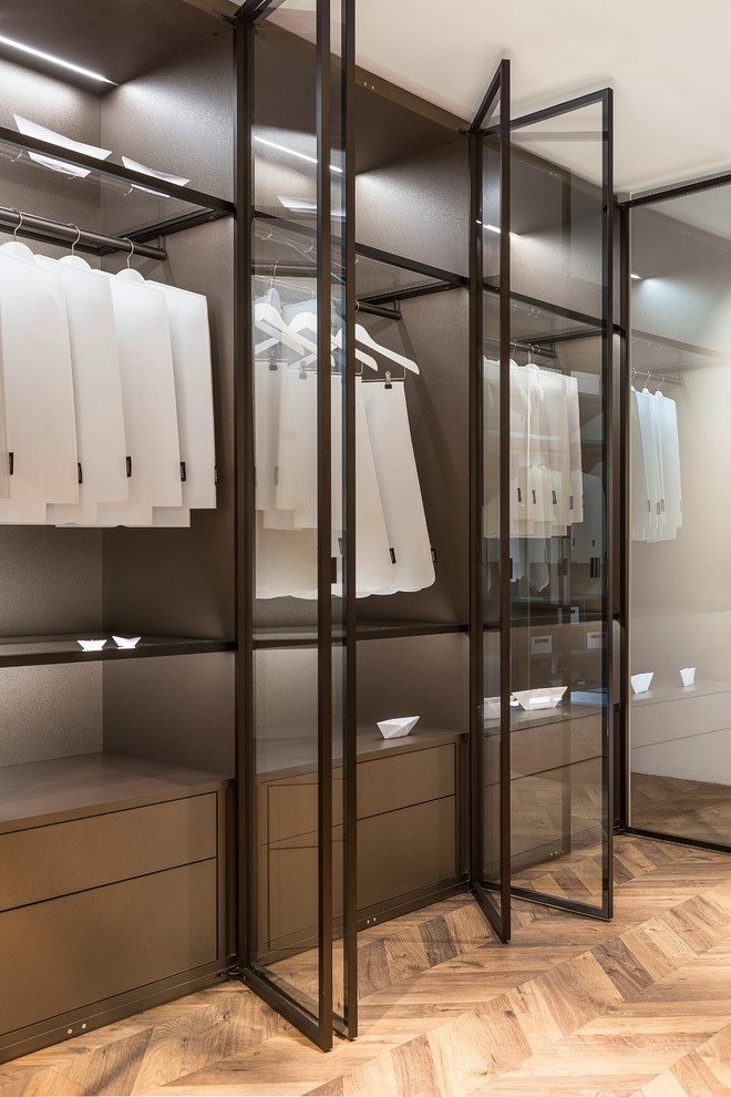 Inspiration for a large modern gender neutral standard wardrobe in Boston with glass-front cabinets, medium wood cabinets, light hardwood flooring and brown floors.