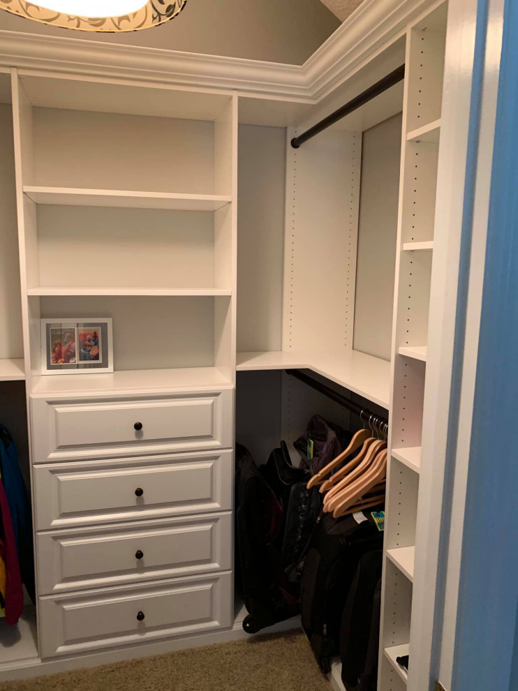 This is an example of a medium sized traditional walk-in wardrobe in Jacksonville with flat-panel cabinets, white cabinets, carpet and brown floors.