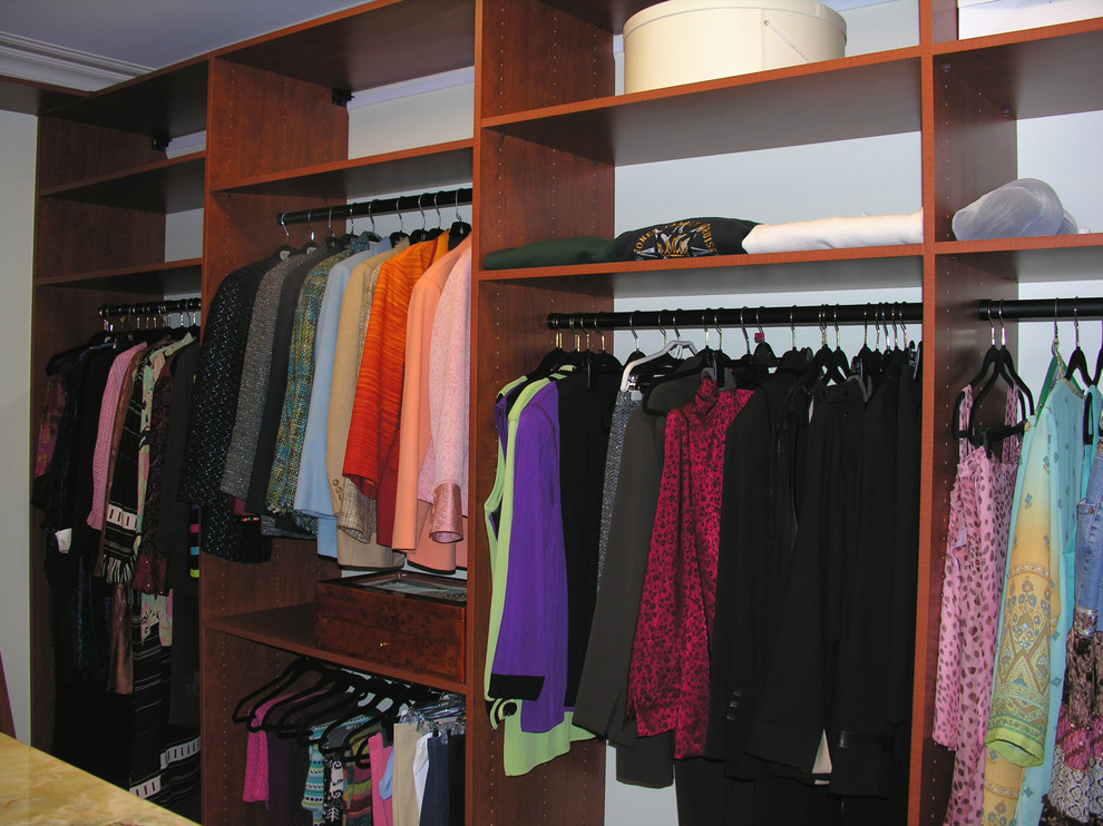 Medium sized classic walk-in wardrobe for women in St Louis with open cabinets and dark wood cabinets.