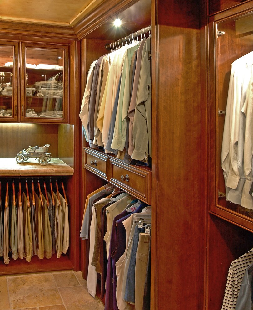 Photo of a medium sized classic gender neutral walk-in wardrobe in Other with recessed-panel cabinets, medium wood cabinets and travertine flooring.