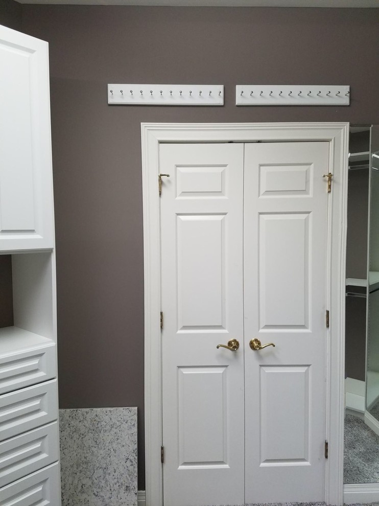 This is an example of a large classic gender neutral walk-in wardrobe in Louisville with raised-panel cabinets, white cabinets, carpet and brown floors.