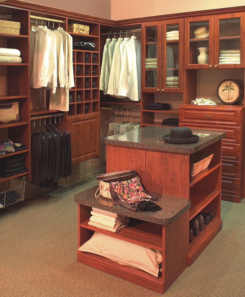 Example of a gender-neutral carpeted walk-in closet design in Philadelphia with raised-panel cabinets and medium tone wood cabinets