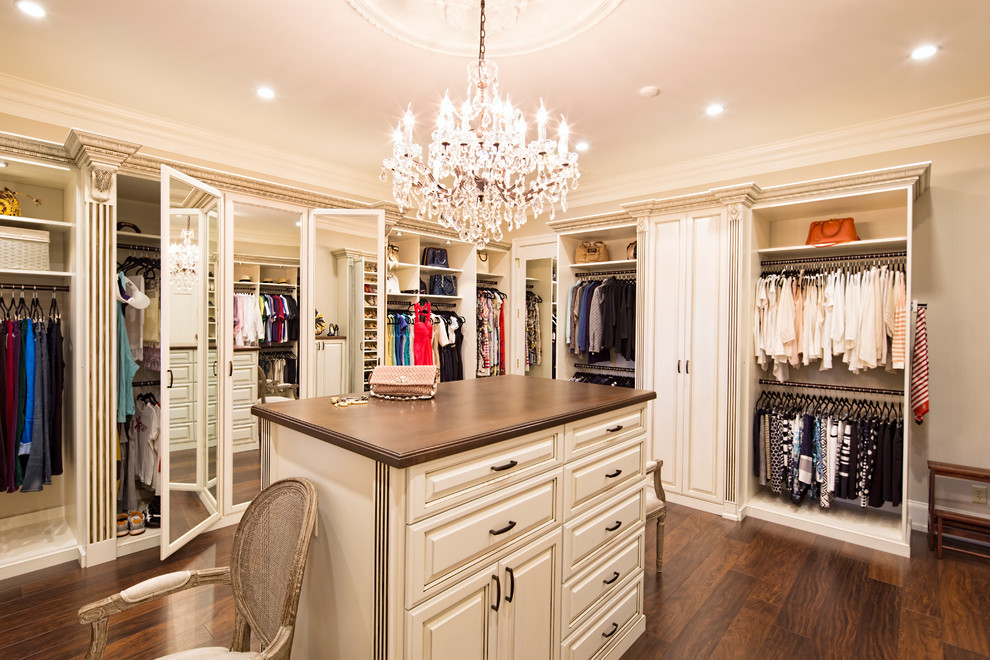 Foto de armario vestidor de mujer clásico grande con puertas de armario blancas, suelo de madera oscura, suelo marrón y armarios con paneles con relieve