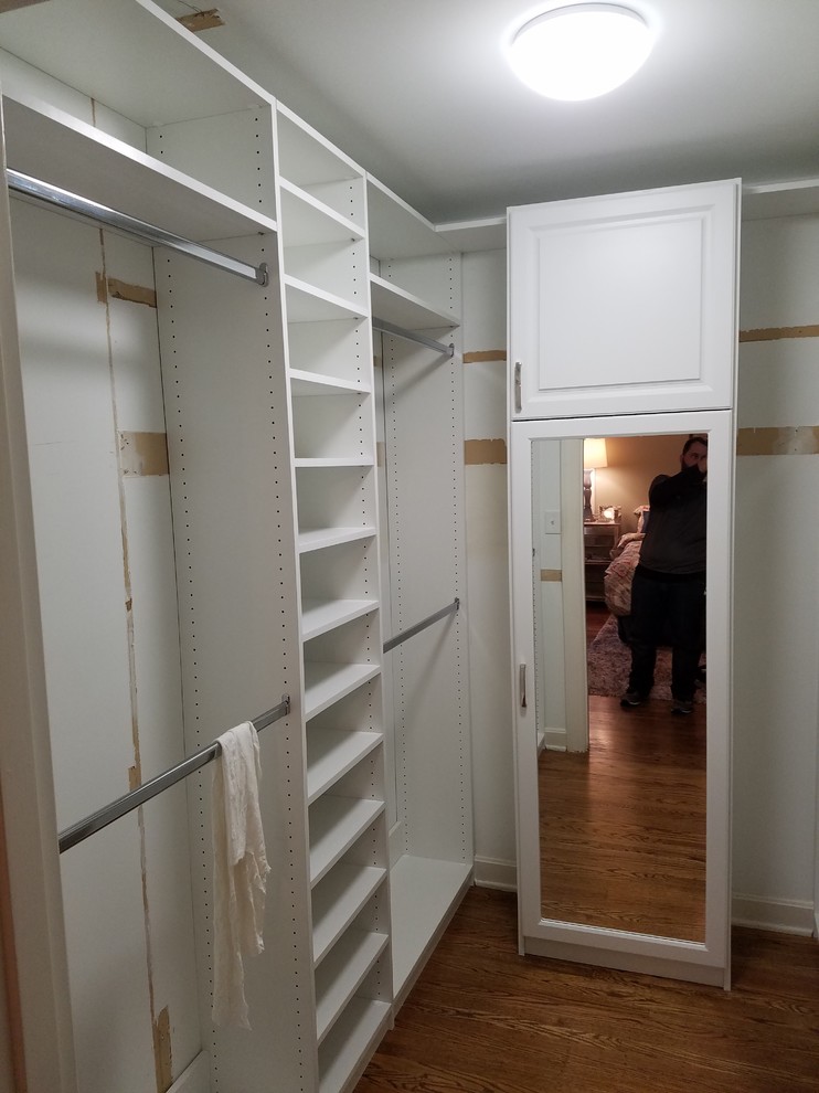 Immagine di una piccola cabina armadio unisex contemporanea con nessun'anta, ante bianche, pavimento in legno massello medio e pavimento marrone