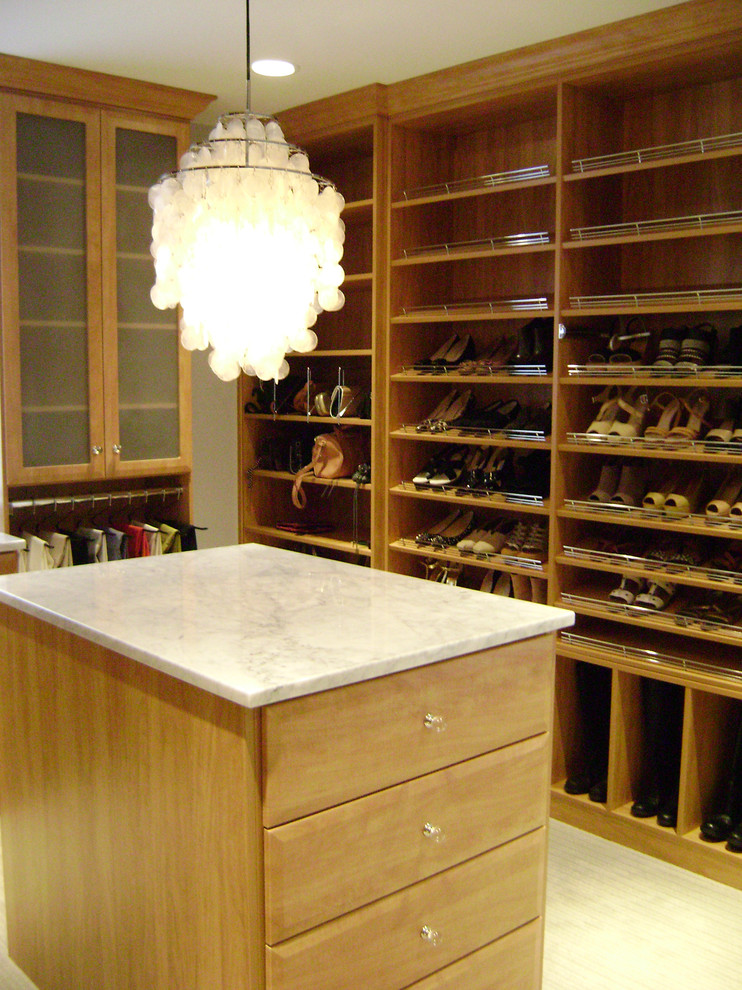 Ejemplo de armario vestidor clásico con armarios tipo vitrina, puertas de armario de madera clara, moqueta y suelo beige