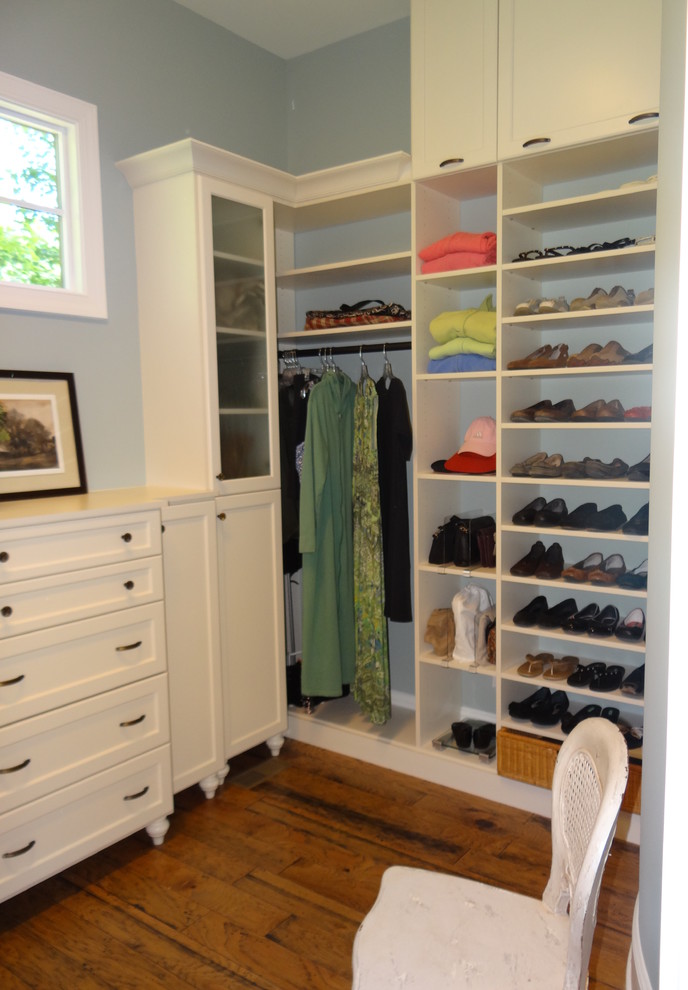 Example of a mid-sized classic gender-neutral medium tone wood floor and brown floor walk-in closet design in Charlotte with recessed-panel cabinets and white cabinets