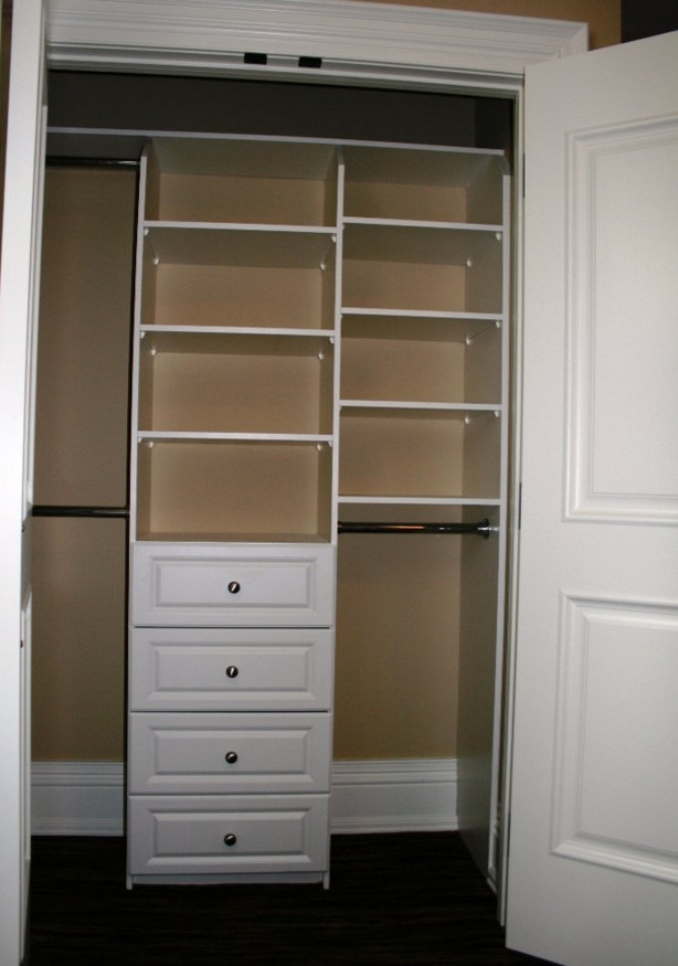 Example of a mid-sized minimalist gender-neutral dark wood floor reach-in closet design in Toronto with raised-panel cabinets and white cabinets