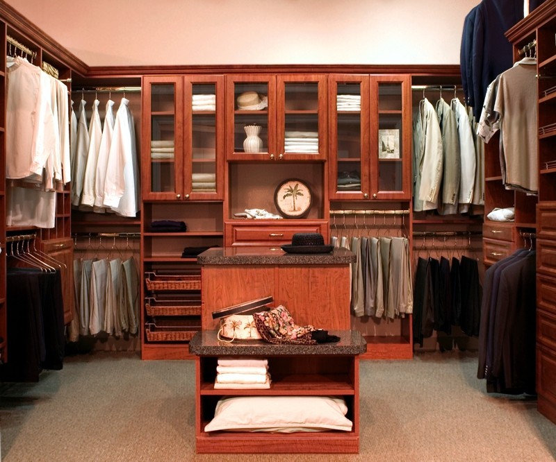Ejemplo de armario vestidor unisex costero de tamaño medio con armarios con paneles con relieve, puertas de armario de madera en tonos medios, moqueta y suelo marrón