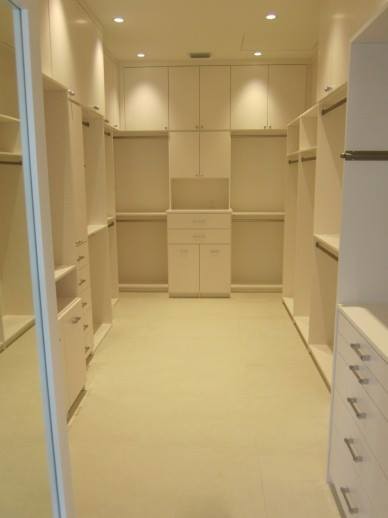 Modelo de armario vestidor unisex actual grande con armarios con paneles lisos, puertas de armario blancas, suelo beige y suelo de baldosas de porcelana