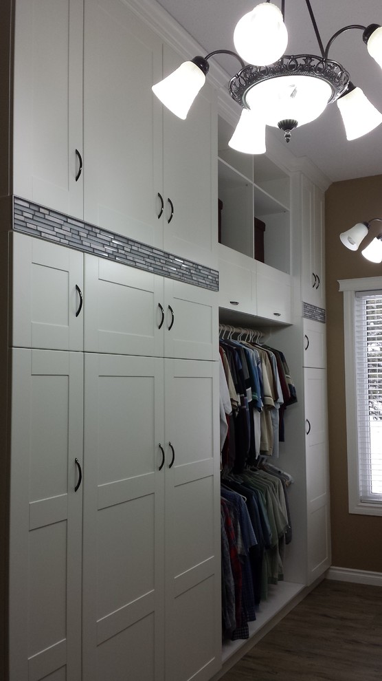 Imagen de vestidor unisex minimalista grande con armarios estilo shaker, puertas de armario blancas, suelo vinílico y suelo marrón