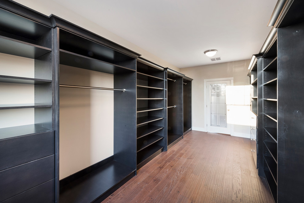Imagen de armario vestidor unisex minimalista de tamaño medio con armarios abiertos, puertas de armario negras, suelo de madera oscura y suelo marrón