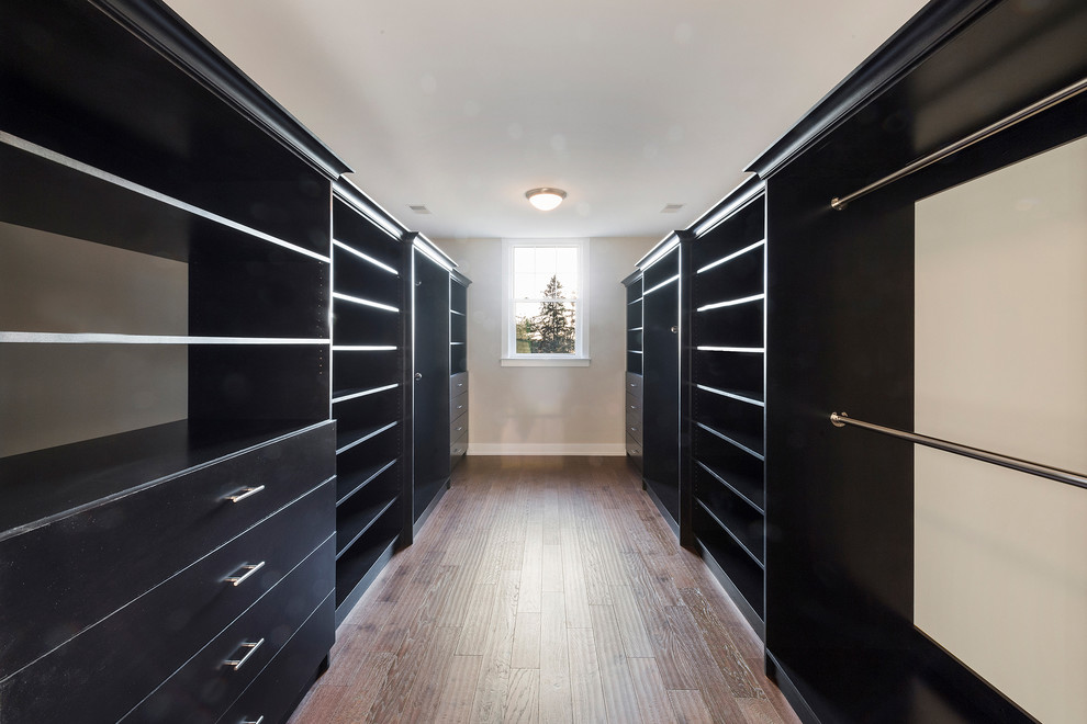 Diseño de armario vestidor unisex minimalista de tamaño medio con armarios abiertos, puertas de armario negras, suelo de madera oscura y suelo marrón
