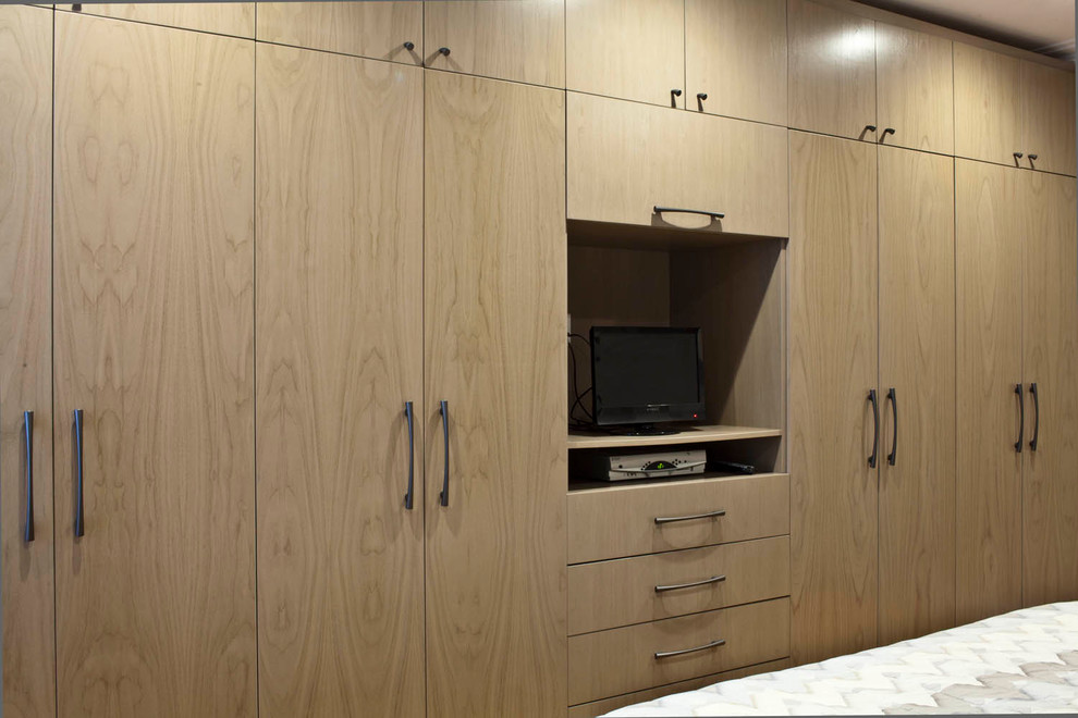 Inspiration for a large contemporary gender-neutral reach-in closet remodel in New York with flat-panel cabinets and medium tone wood cabinets