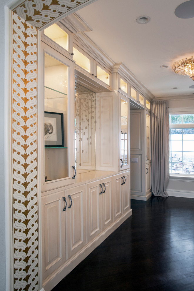 Idée de décoration pour un grand dressing room tradition pour une femme avec des portes de placard blanches, parquet foncé et un placard avec porte à panneau surélevé.