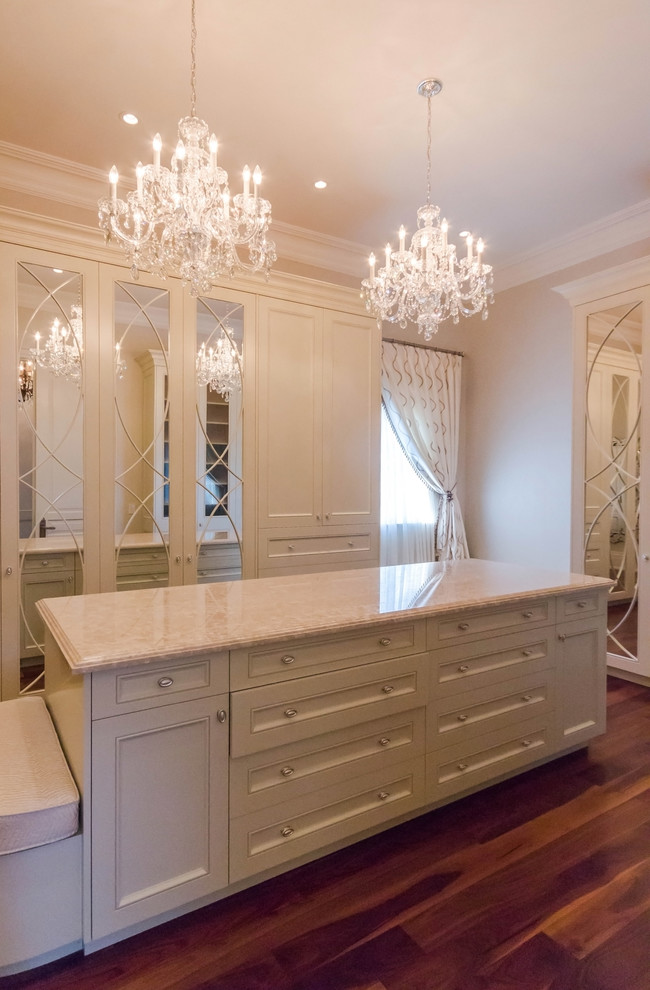 Expansive classic gender neutral walk-in wardrobe in Toronto with recessed-panel cabinets, beige cabinets, dark hardwood flooring and brown floors.