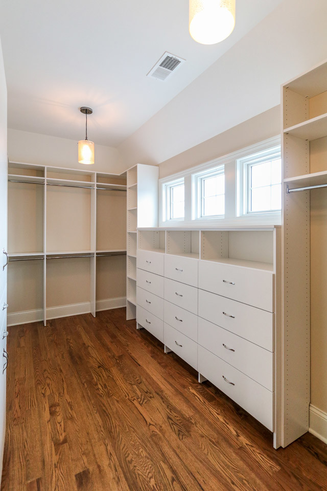 Imagen de armario vestidor clásico extra grande con armarios con paneles lisos, puertas de armario de madera clara y suelo de madera clara