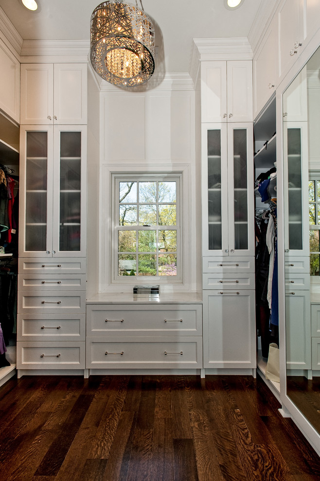 На фото: гардеробная комната в стиле неоклассика (современная классика) с белыми фасадами с