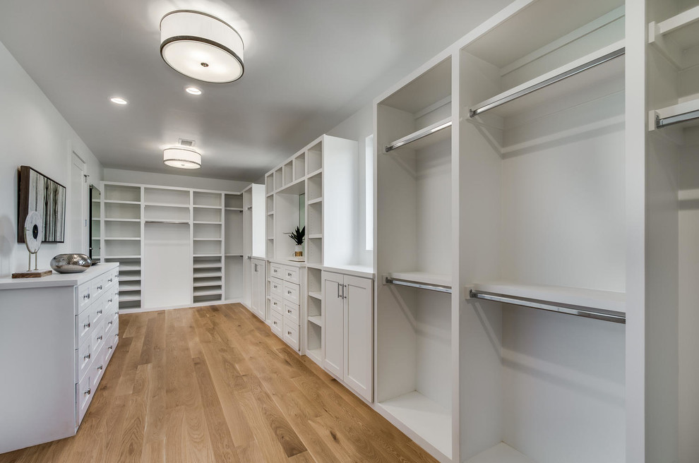 Design ideas for a large classic gender neutral walk-in wardrobe in Denver with shaker cabinets, white cabinets and medium hardwood flooring.