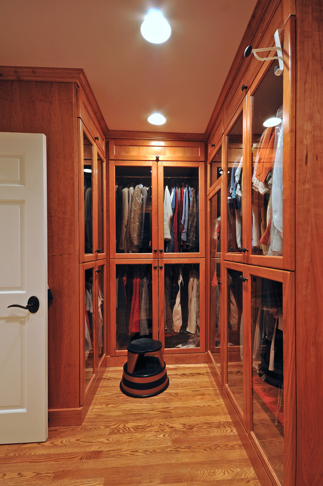 Example of a large classic gender-neutral light wood floor walk-in closet design in Boston with flat-panel cabinets and dark wood cabinets