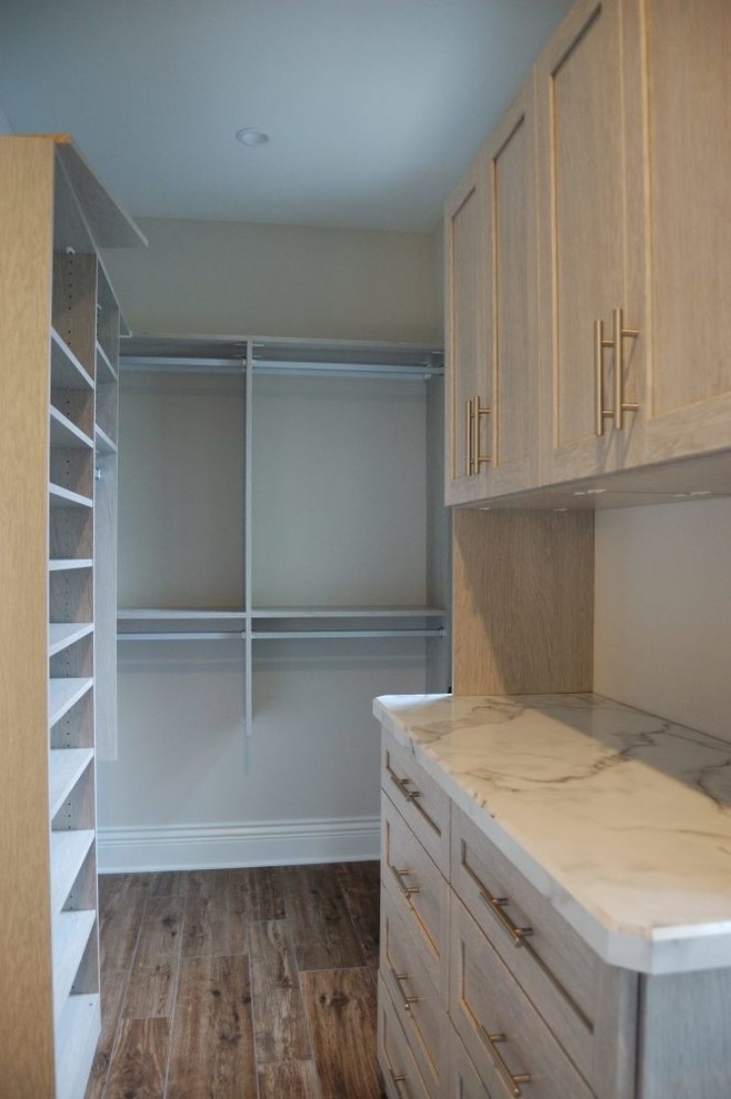 Example of a mid-sized transitional ceramic tile walk-in closet design in New York with shaker cabinets and light wood cabinets