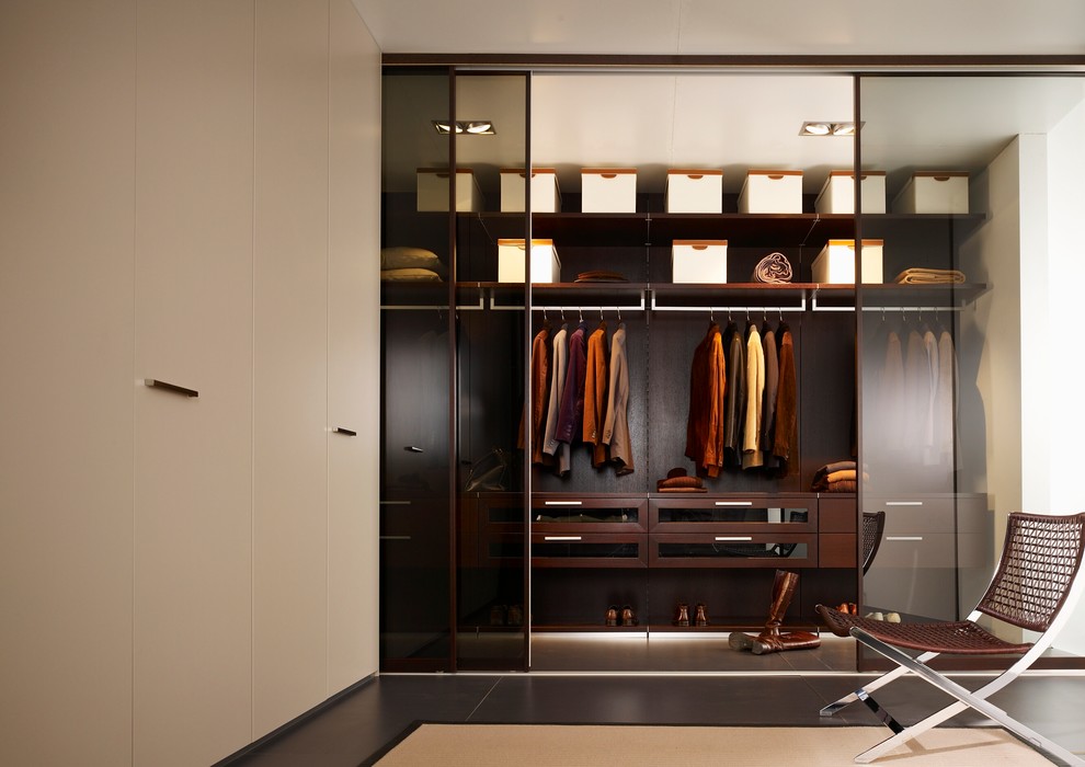 Immagine di una cabina armadio unisex minimalista di medie dimensioni con ante di vetro, ante in legno bruno e pavimento in gres porcellanato