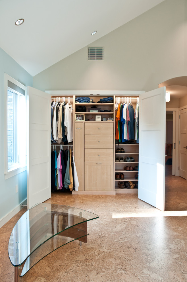 Imagen de armario y vestidor unisex pequeño con a medida, puertas de armario de madera clara y suelo marrón