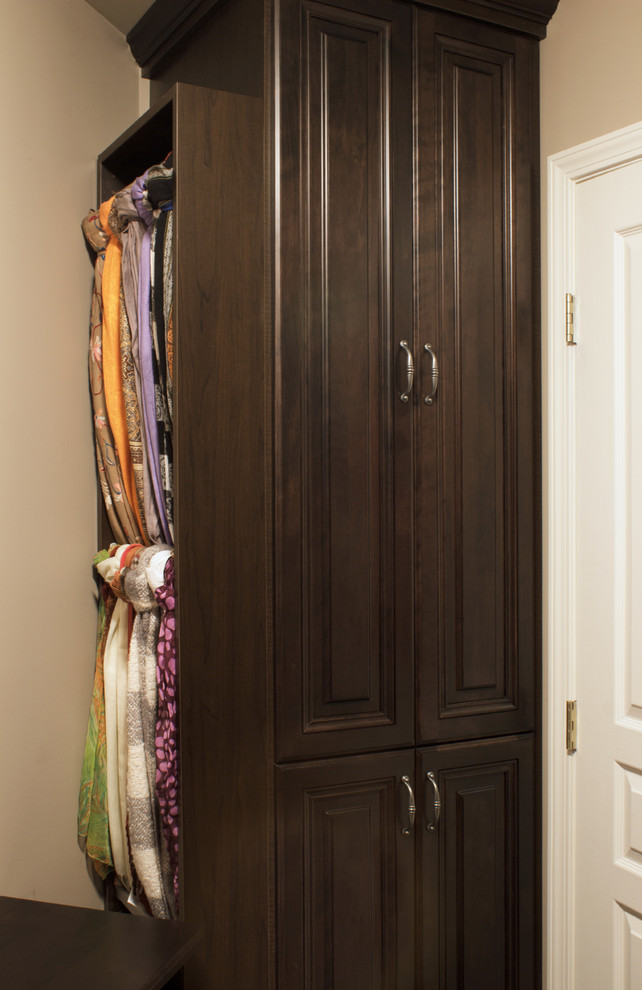 Ejemplo de armario vestidor de mujer clásico pequeño con armarios con paneles con relieve, puertas de armario de madera en tonos medios y suelo de madera oscura