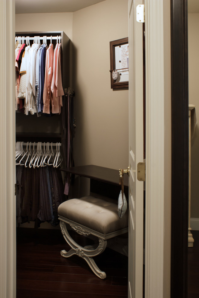 Modelo de armario vestidor de mujer clásico pequeño con armarios con paneles con relieve, puertas de armario de madera en tonos medios y suelo de madera oscura