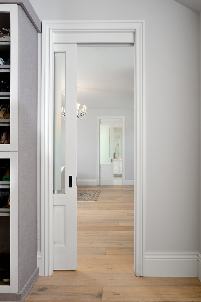 Medium sized contemporary standard wardrobe for women in Toronto with shaker cabinets, white cabinets, light hardwood flooring and beige floors.