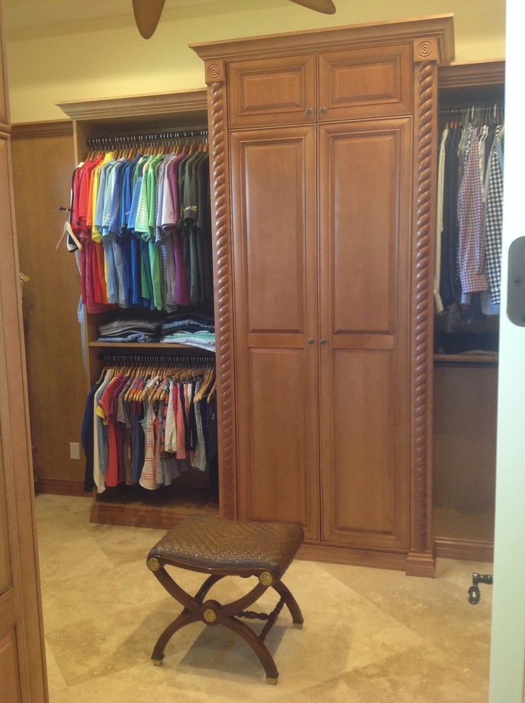 Diseño de armario vestidor unisex tradicional de tamaño medio con armarios con paneles con relieve, puertas de armario de madera oscura y suelo de baldosas de cerámica