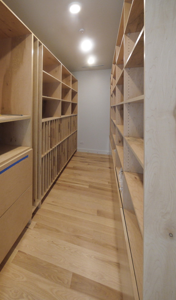 Imagen de armario vestidor minimalista grande con armarios con paneles lisos, puertas de armario de madera clara y suelo de madera en tonos medios
