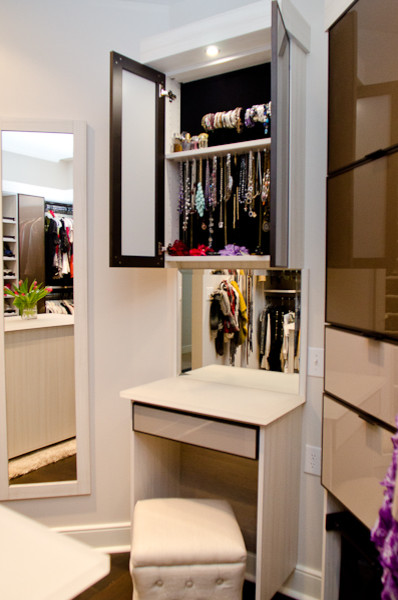 Imagen de armario vestidor de mujer actual de tamaño medio con armarios abiertos, puertas de armario marrones y suelo de madera oscura