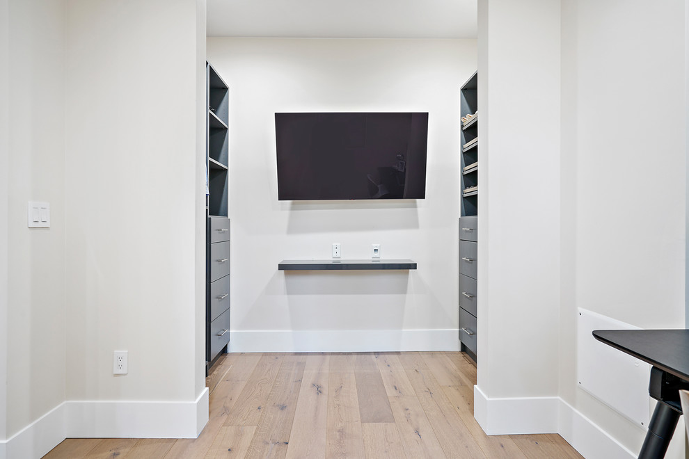 Ejemplo de armario vestidor unisex minimalista con armarios con paneles empotrados, puertas de armario azules, suelo de madera clara y suelo beige